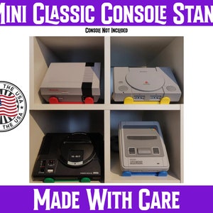 May include: A white shelf unit with four compartments, each holding a different retro video game console. The consoles are a Nintendo Entertainment System, a Sega Genesis, a Super Nintendo Entertainment System, and a Sony PlayStation. The text "MINI CLASSIC CONSOLE STAND" is at the top of the image, and the text "MADE WITH CARE" is at the bottom of the image.