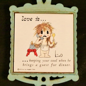 May include: A blue and white ceramic trivet with a cartoon illustration of a woman on the phone. The text reads "love is... keeping your cool when he brings a guest for dinner."  The trivet is decorated with a scalloped border.