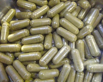 May include: A large collection of cylindrical capsules filled with a fine, olive-green herbal powder. Each capsule features a smooth, semi-translucent shell that reveals the granular texture of the contents packed tightly inside.