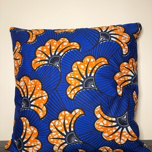 May include: A blue and orange patterned throw pillow with a floral design. The pillow is made of a soft, comfortable fabric and is perfect for adding a touch of color and style to any room.