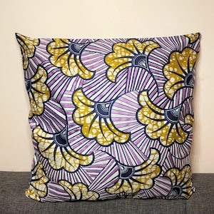 May include: A square throw pillow with a purple and white background featuring a repeating pattern of yellow stylized flowers.