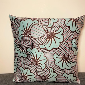 May include: A square throw pillow with a brown and teal floral pattern. The pillow has a light brown background with teal flowers and a white center. The flowers have a striped pattern in shades of brown and purple.