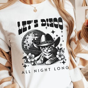 May include: White t-shirt featuring a black and white graphic of a cat wearing a cowboy hat in front of a disco ball. The text "Let's Disco All Night Long" is printed on the shirt.