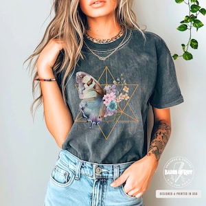 May include: A dark gray t-shirt with a graphic of a butterfly and flowers inside a geometric shape. The text "remarkable things" is printed on the shirt.
