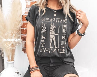 Koszulka z mitologii egipskiej Anubis Koszulka z hieroglifami egipskimi Koszulka z Okiem Horusa Koszulka Ankh Koszulka Anubis i egipska bogini Nebthet Koszulka Neftyda