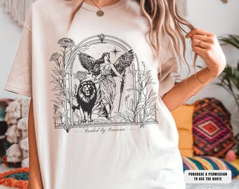May include: Beige t-shirt featuring a black and white illustration of a winged figure, a lion, and floral elements within an arched frame. The text "Guided by Inanna" is below the illustration. The shirt also has the text "Babes of Riot" and "Purchase a permission to use the quote".