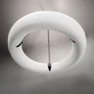 May include: A white circular pendant light fixture with a chain hanging from the center. The fixture is made of a textured material and has a simple, modern design.