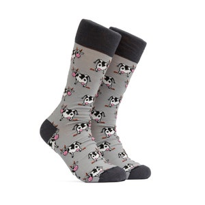 May include: A pair of gray socks with a repeating pattern of cartoon cows in black and white. The socks have dark gray heels, toes, and cuffs. The cows have pink udders and horns.