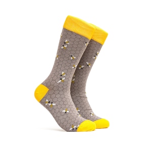 May include: A pair of gray socks with a honeycomb pattern and yellow bees. The socks have yellow tops.