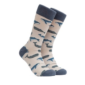May include: A pair of beige socks with a blue whale pattern. The socks have a blue cuff and are made of a soft, comfortable material.