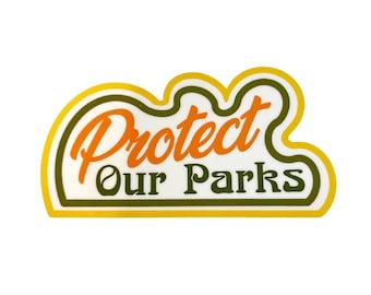 May include: A sticker with the words "Protect Our Parks" in orange and green, outlined in yellow and green. The sticker has a cloud-like shape and is on a white background.
