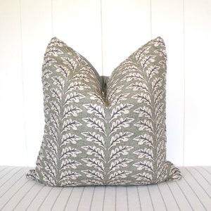 Puede incluir: Una almohada de tiro verde y blanca con un dise&ntilde;o de hojas. La almohada est&aacute; hecha de una tela suave y texturizada.