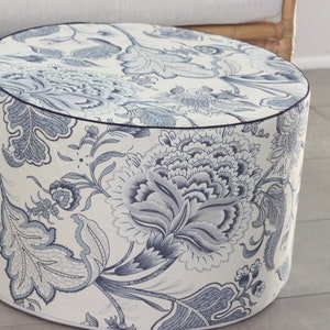 K&ouml;nnte beinhalten: Ein runder, wei&szlig;er Hocker mit einem blauen und wei&szlig;en Blumenmuster. Der Hocker hat einen dunkelblauen Rand oben.