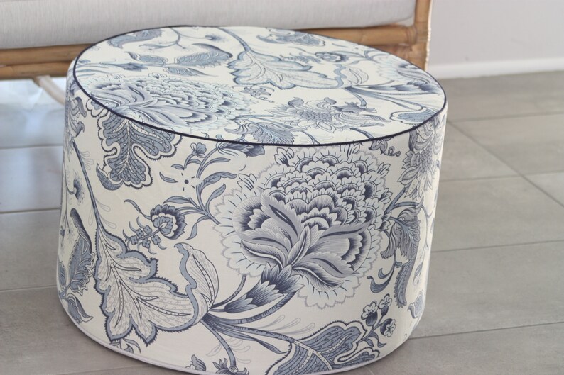 K&ouml;nnte beinhalten: Ein runder, wei&szlig;er Hocker mit einem blauen und wei&szlig;en Blumenmuster. Der Hocker hat einen dunkelblauen Rand oben.
