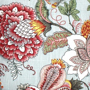 May include: A light blue fabric featuring a dense botanical print with large, layered red and white flowers, smaller pink and white blossoms, and green leaves. The pattern includes intricate yellow accents and thin, dark brown stems.