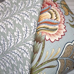Puede incluir: Dos almohadas decorativas con patrones florales. Una almohada tiene un fondo verde claro con dise&ntilde;os de hojas blancas. La otra almohada tiene un fondo azul claro con un dise&ntilde;o floral colorido.