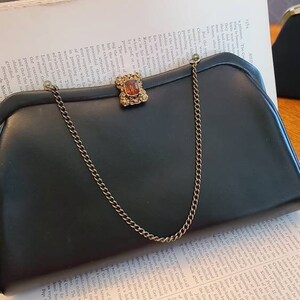 Precioso bolso de mano de piel negra con bonito cierre y asa de cadena, estilo retro