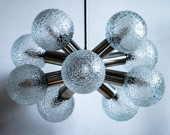May include: A silver and glass chandelier with eight textured glass globes. The chandelier has a modern design and is suspended from a single chain.