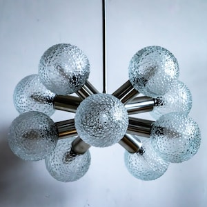 May include: A silver and glass chandelier with eight textured glass globes. The chandelier has a modern design and is suspended from a single chain.