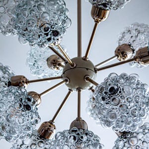 May include: A brass and glass chandelier with eight light bulbs. The glass shades are clear and have a bubbled texture.