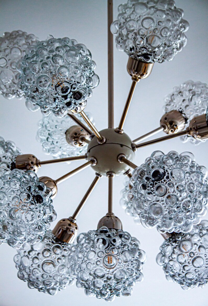 May include: A brass and glass chandelier with eight light bulbs. The glass shades are clear and have a bubbled texture.
