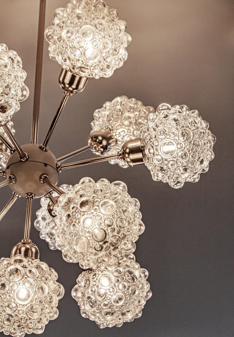 May include: A chrome and glass chandelier with six bubble-shaped light fixtures. The chandelier has a modern design and is perfect for a mid-century modern home.