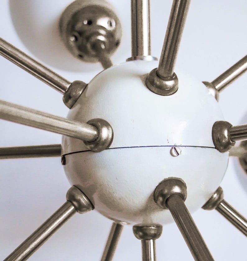 May include: A white globe chandelier with multiple silver metal arms extending outwards. The globe has a smooth, slightly textured surface.