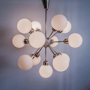 May include: A modern, chrome and white glass chandelier with multiple globe-shaped lights.