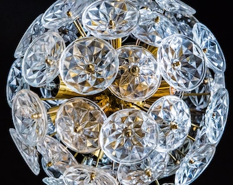 May include: A gold-toned chandelier with a spherical shape, featuring numerous clear glass crystal-like pieces. The chandelier has a modern design and is perfect for adding a touch of elegance to any room.