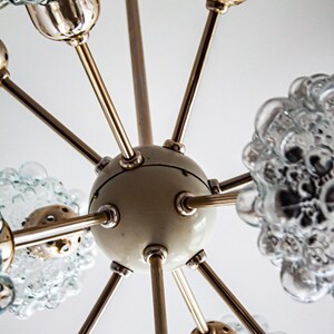 May include: A vintage brass and glass chandelier with a white center and multiple arms. Each arm has a clear glass globe with a bubbled texture.