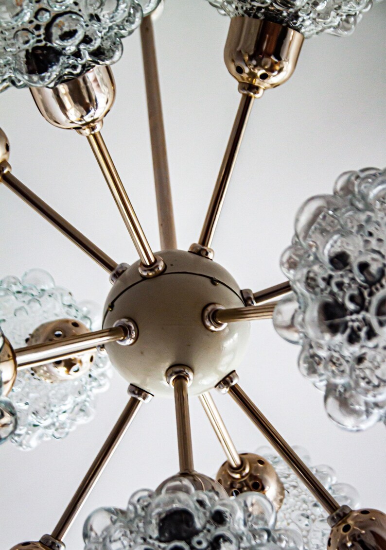 May include: A vintage brass and glass chandelier with a white center and multiple arms. Each arm has a clear glass globe with a bubbled texture.