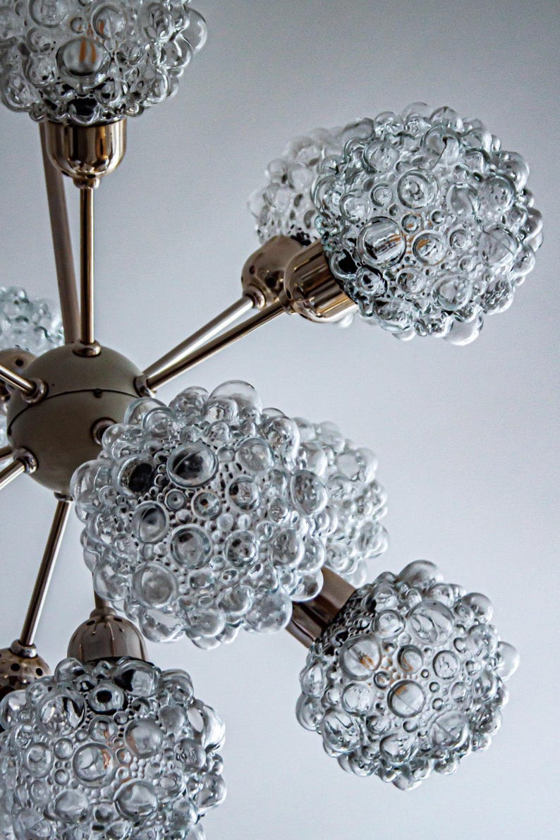 May include: A chrome and glass chandelier with six light fixtures. Each fixture has a clear glass shade with a bubbled texture.