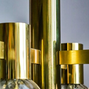 May include: A brass chandelier with multiple globe-shaped glass shades. The chandelier has a polished brass finish and a modern design.
