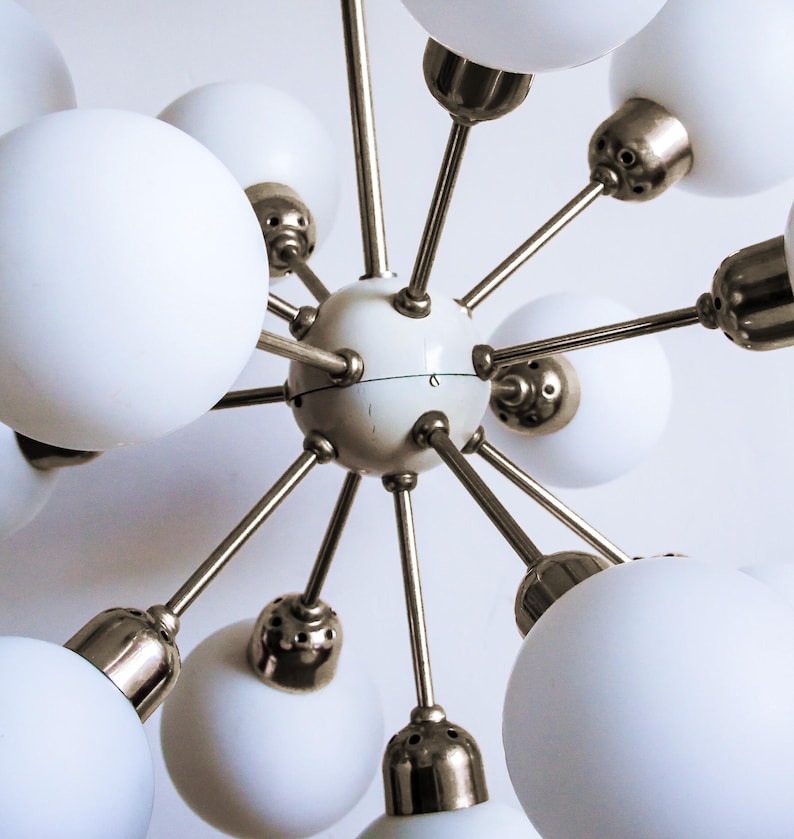 May include: A white and gold mid-century modern chandelier with multiple globe-shaped light fixtures.
