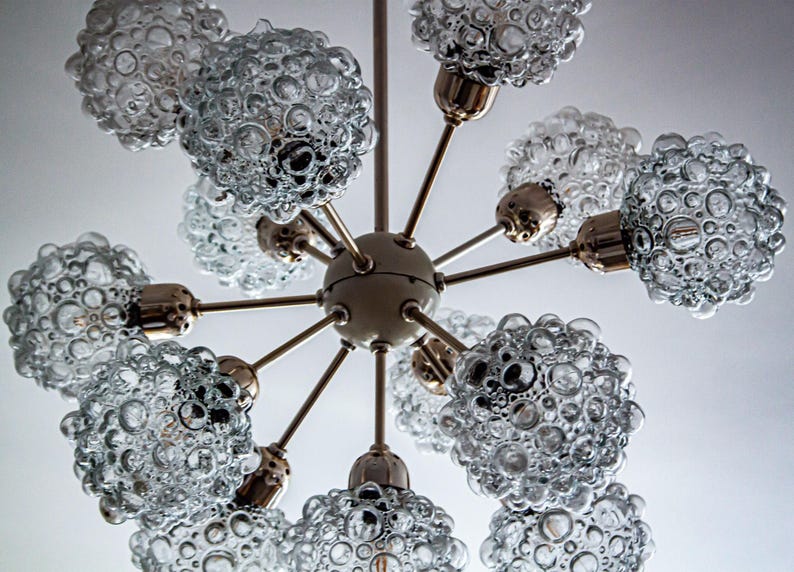 May include: A brass and glass chandelier with eight light bulbs. The glass shades are clear and have a bubbled texture.