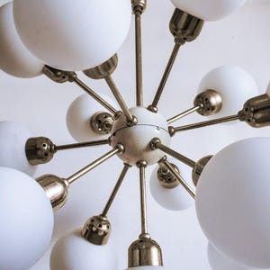 May include: A brass and white mid-century modern chandelier with 12 white glass globe shades.