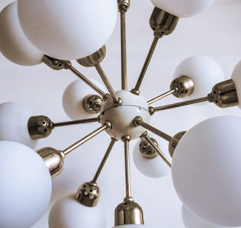 May include: A brass and white mid-century modern chandelier with 12 white glass globe shades.