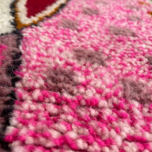 Op de afbeelding: Close-up van een roze en wit pluche tapijt met een textuur. Het tapijt heeft een subtiel patroon van roze en wit.