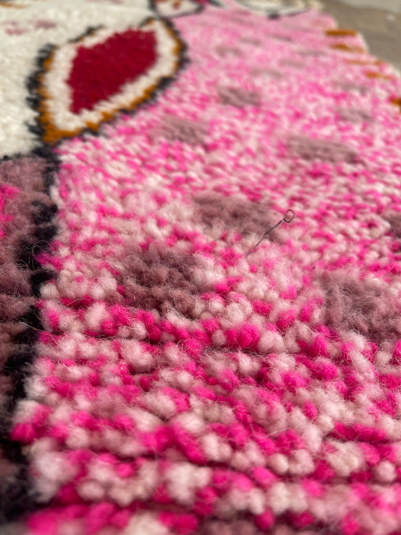 Op de afbeelding: Close-up van een roze en wit pluche tapijt met een textuur. Het tapijt heeft een subtiel patroon van roze en wit.