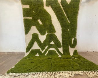 May include: A green and white rug with a geometric pattern. The rug has a fringe border.