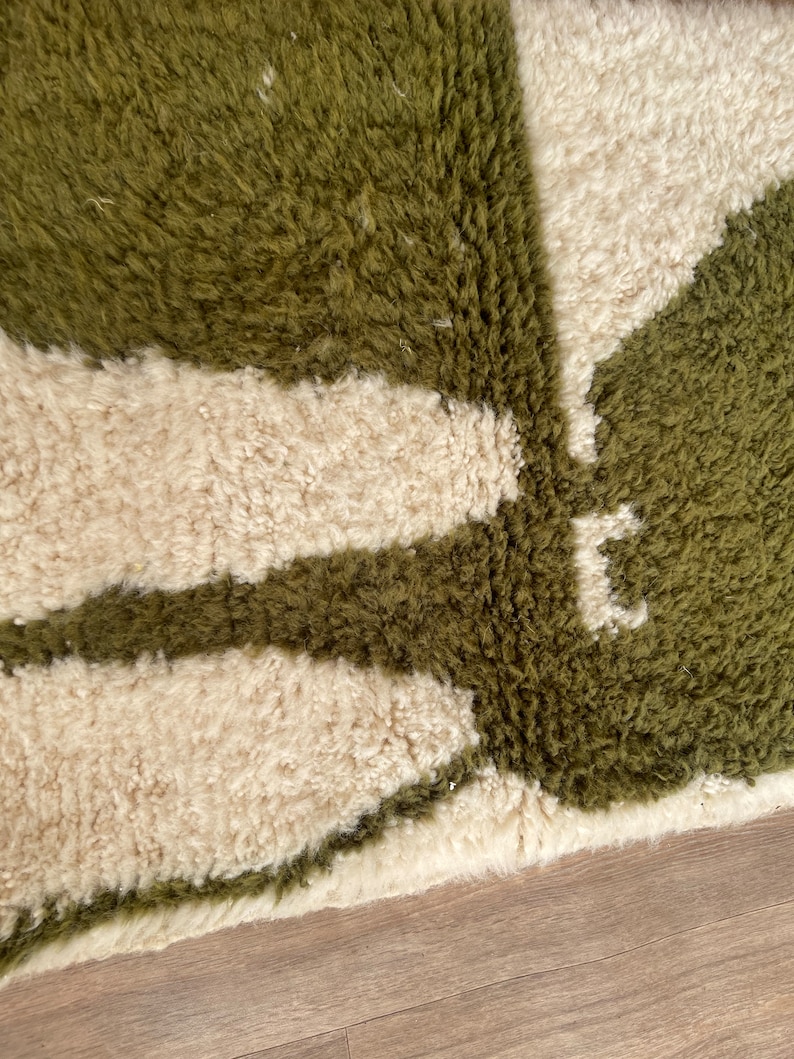Pode incluir: Close-up de um tapete felpudo verde e branco com um padr&atilde;o geom&eacute;trico. O tapete tem uma pilha grossa e uma textura macia.