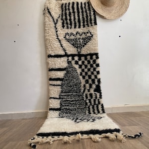 May include: A black and white patterned rug with a geometric design. The rug is made of wool and has a fringe border.