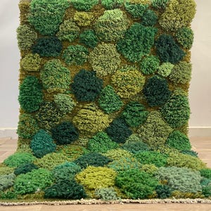 May include: A green textured rug with a design reminiscent of a mossy landscape. The rug features a pattern of raised, rounded shapes in various shades of green. The color palette includes light and dark greens, with a hint of yellow, creating a natural look.