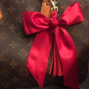 Foulard tressé avec noeud rouge cerise uni et pompon rouge . Clip doré sur la quincaillerie de votre sac, accessoire de breloque pour poignée