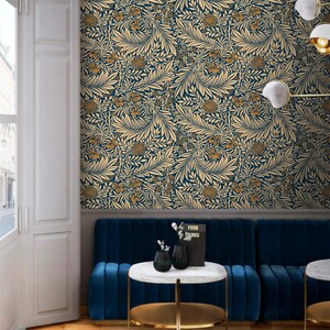 May include: A blue velvet sofa with gold trim sits in front of a wall covered in a blue and gold floral wallpaper. The sofa is accented with two small black vases and a book titled "Food & Drinks".