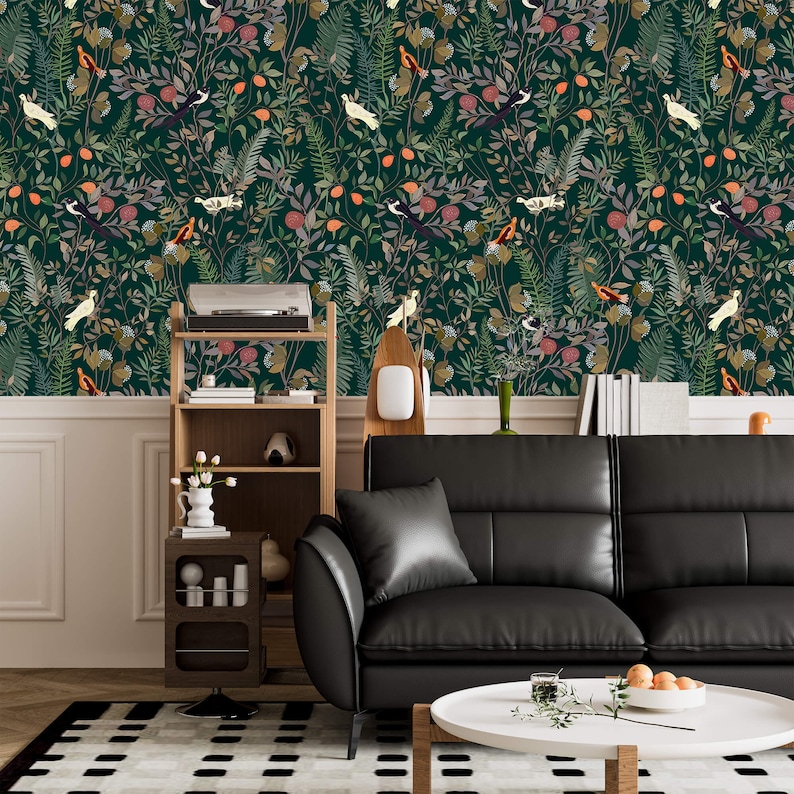 K&ouml;nnte beinhalten: Eine dunkelgr&uuml;ne Tapete mit einem sich wiederholenden Muster aus V&ouml;geln, Bl&auml;ttern und Blumen. Die Tapete ist in einem Wohnzimmer mit einem schwarzen Ledersofa, einem Holzregal und einem Couchtisch zu sehen.