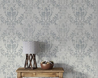 May include: A wooden table with a decorative lamp and a bowl. The lamp has a gray and white chevron pattern shade. The bowl contains decorative items. The background is a white wall with a blue floral pattern.
