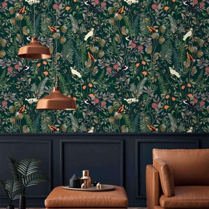 K&ouml;nnte beinhalten: Eine dunkelgr&uuml;ne Tapete mit einem sich wiederholenden Muster aus V&ouml;geln, Bl&auml;ttern und Blumen. Die Tapete ist in einem Raum mit einem braunen Ledersofa und einem Couchtisch zu sehen.