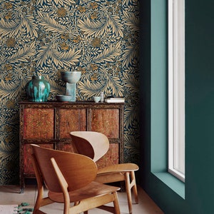 May include: Two wooden chairs with a unique design sit in a room with teal walls and a patterned wallpaper. The wallpaper features a floral design with gold and blue colors.