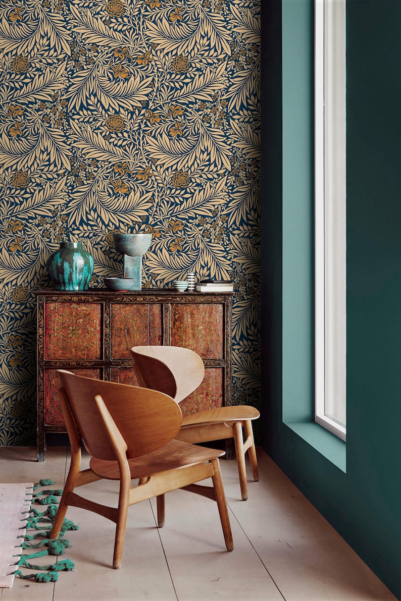 May include: Two wooden chairs with a unique design sit in a room with teal walls and a patterned wallpaper. The wallpaper features a floral design with gold and blue colors.